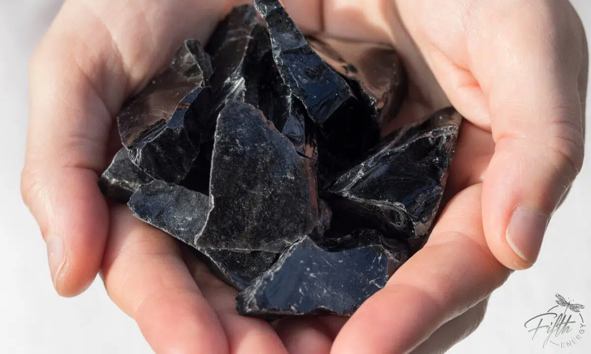 Meaning of Obsidian gemstone hand holding raw obsidians
