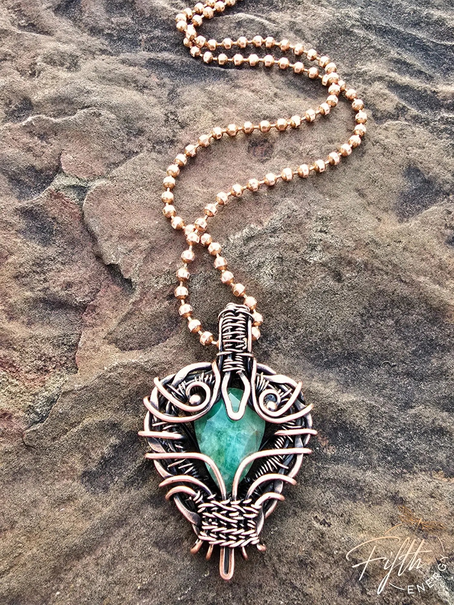 Copper Encased Emerald Necklace 2 A one-of-a-kind emerald necklace handcrafted in the USA, featuring a natural emerald gemstone encased in polished American-made copper. The artisan design showcases unique wirework and sustainable materials.