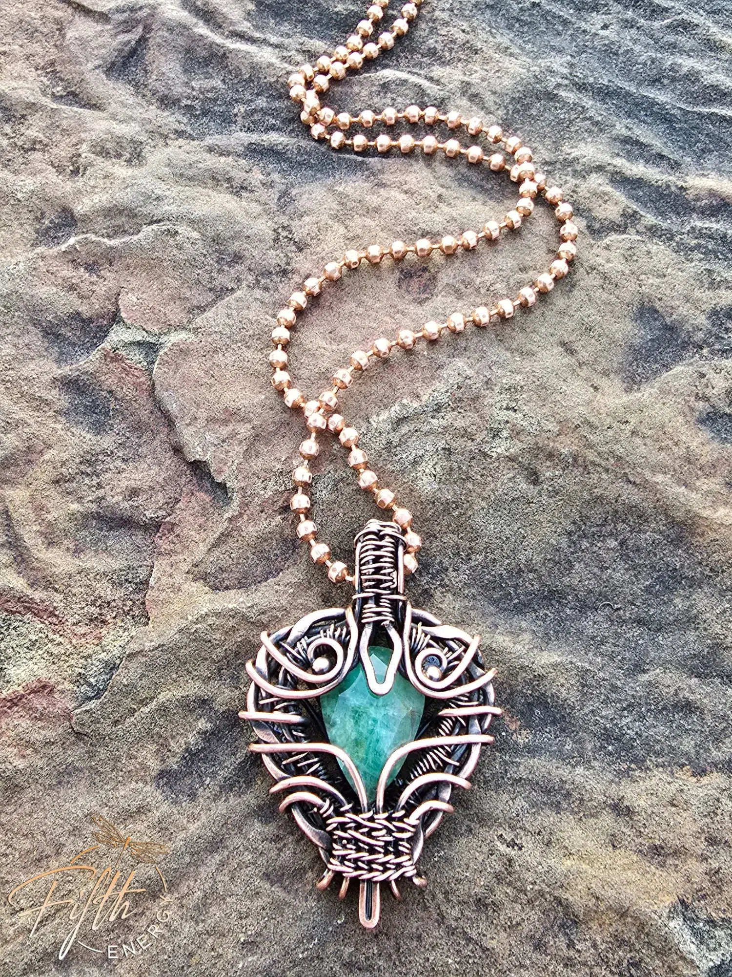 Copper Encased Emerald Necklace 3 A one-of-a-kind emerald necklace handcrafted in the USA, featuring a natural emerald gemstone encased in polished American-made copper. The artisan design showcases unique wirework and sustainable materials.