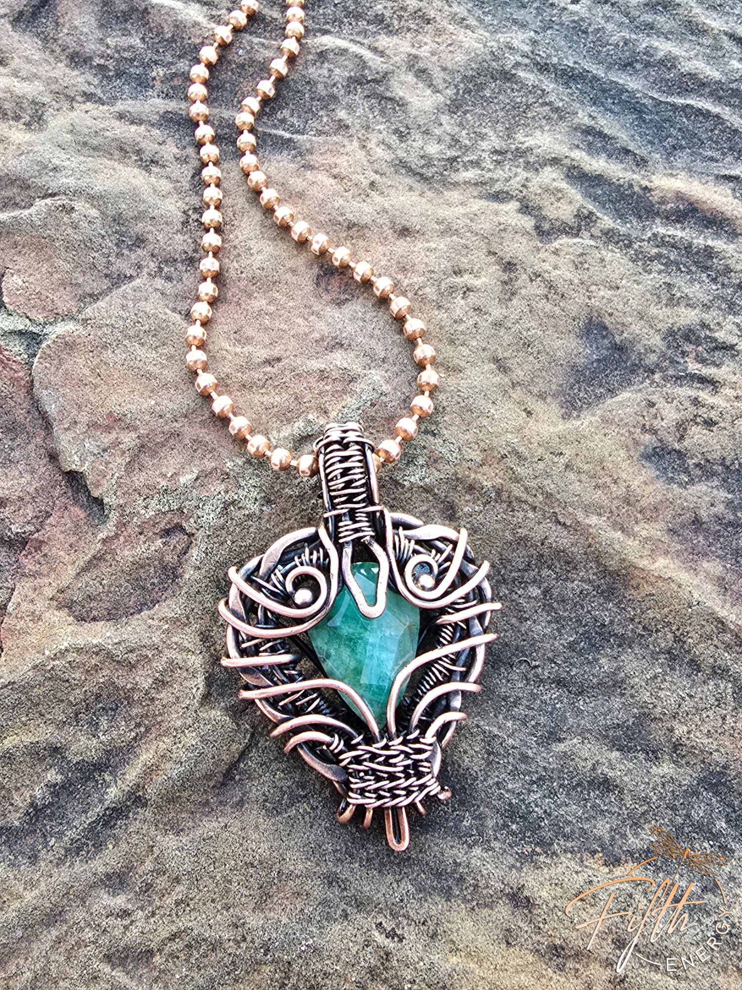 Copper Encased Emerald Necklace 5 Artistic display of an American-made copper necklace with a genuine emerald centerpiece. This handmade USA-crafted jewelry piece highlights intricate copperwork and a rare, one-of-a-kind gemstone.