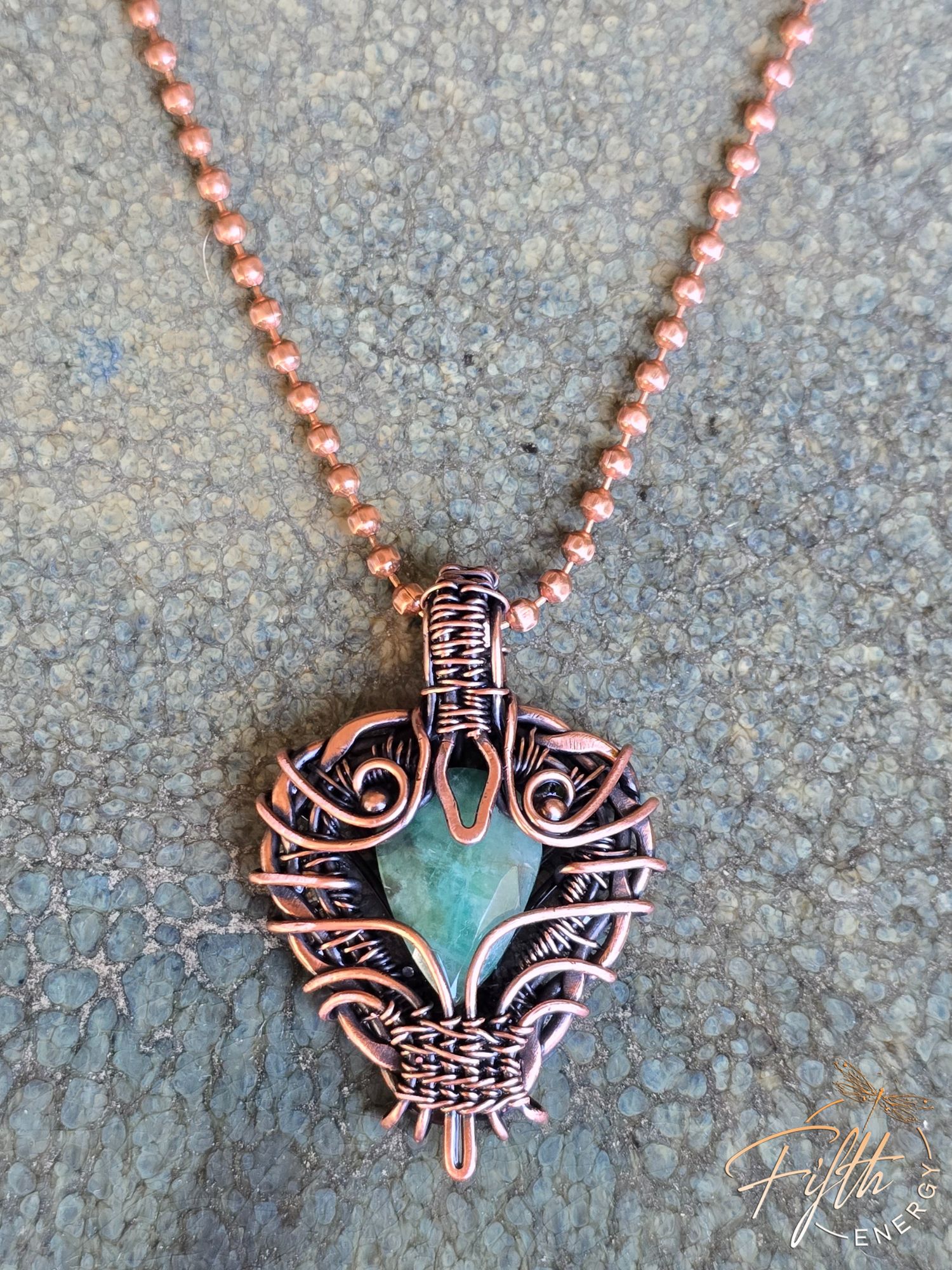 Copper Encased Emerald Necklace 10 Copper Encased Emerald Necklace a one-of-a-kind emerald necklace handcrafted in the USA, featuring a natural emerald gemstone encased in polished American-made copper. The artisan design showcases unique wirework and sustainable materials.